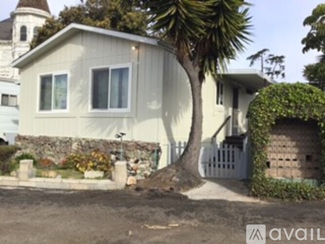 A house with a white fence and a tree in front.