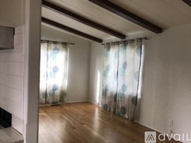 A room with wooden floors and a window with curtains.
