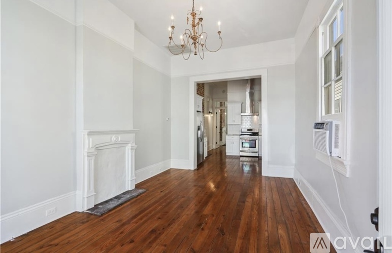 A large, empty room with a fireplace and a chandelier.