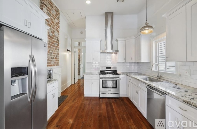 A kitchen with white cabinets and a brick wall.