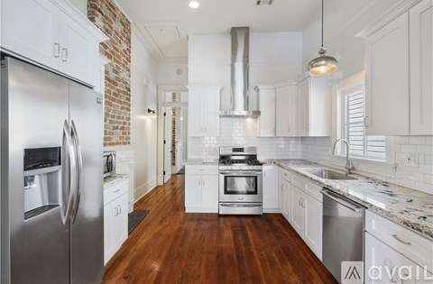 A kitchen with white cabinets and a brick wall.