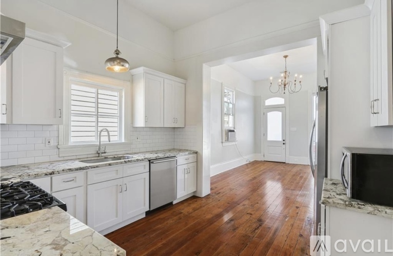 A kitchen with white cabinets and a marble countertop.