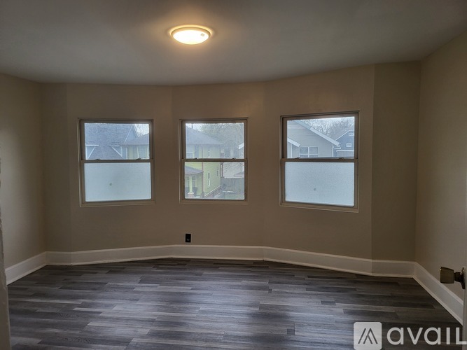 A room with a grey floor and three windows.