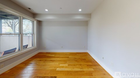 A room with wooden flooring and a window with a view of trees.