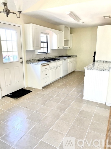 A kitchen with white cabinets and a granite countertop.