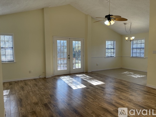 A spacious room with wooden floors and a ceiling fan.