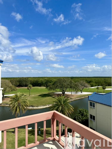A balcony overlooks a green landscape with a body of water and a building in the distance.