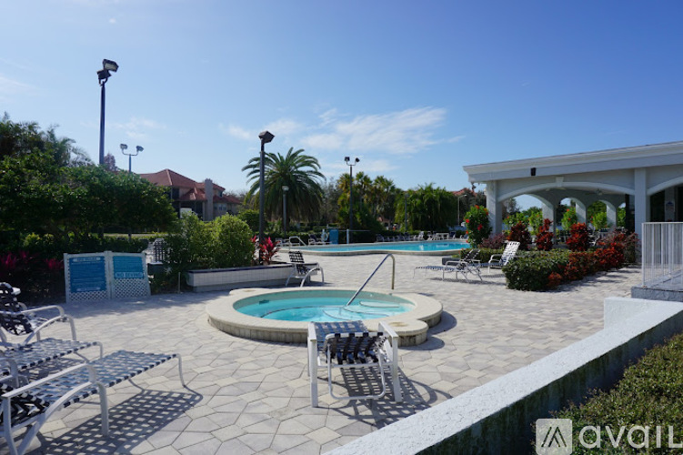 A pool with a hot tub and lounge chairs in the foreground with a building in the background.
