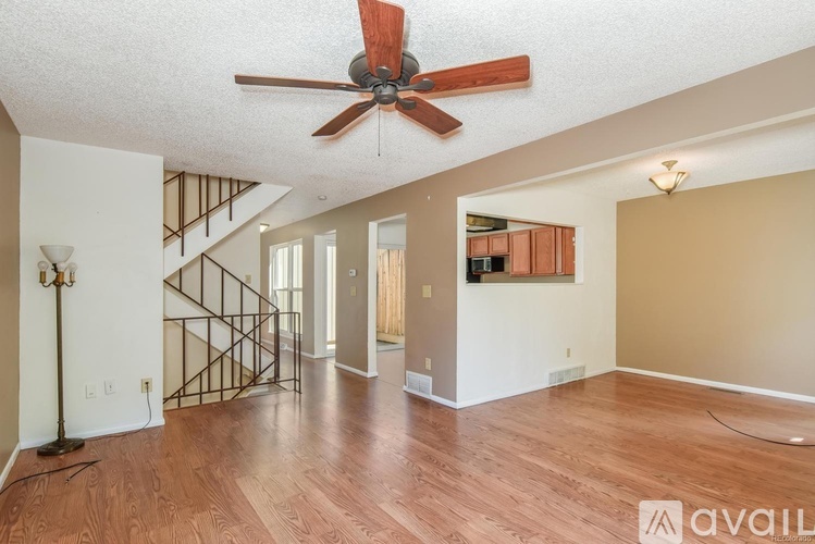 A room with a fan and wooden floors.