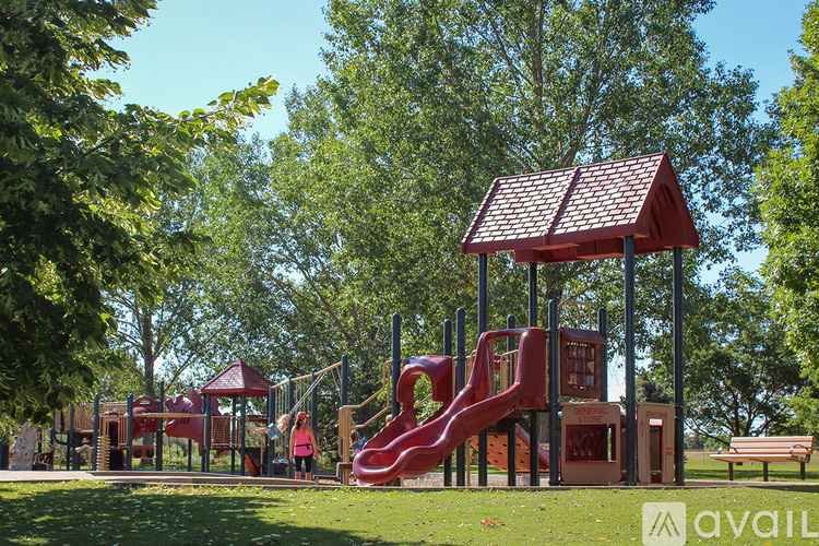 A playground with a red slide and a red roofed structure.