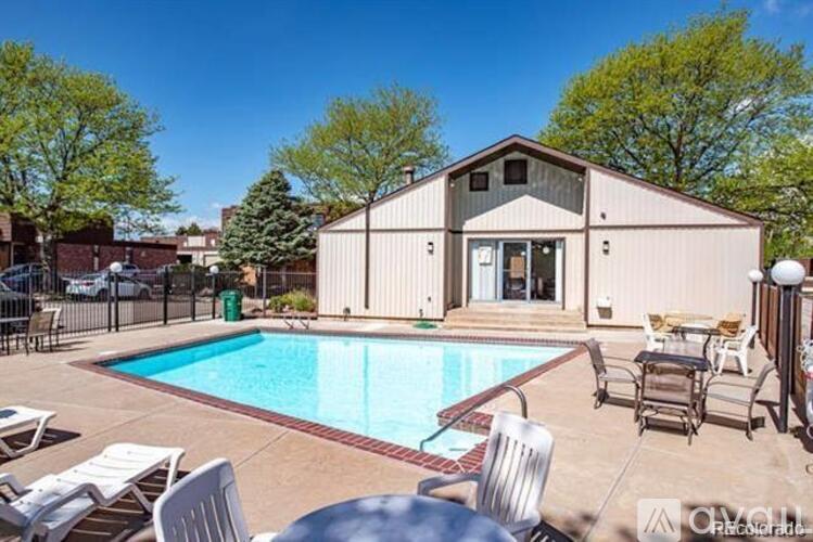 A pool with chairs and a house in the background.