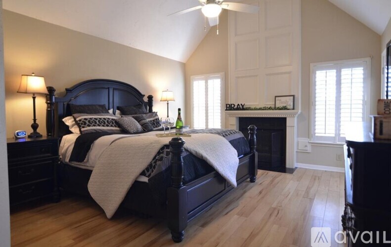 A bedroom with a dark bed and a fireplace with the word "DRAY" written above it.