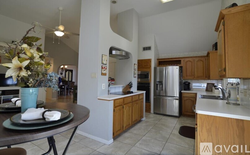 A kitchen with a table set for two and a vase of flowers.