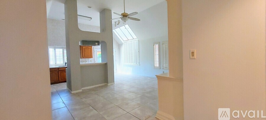 A spacious room with a ceiling fan and a skylight.
