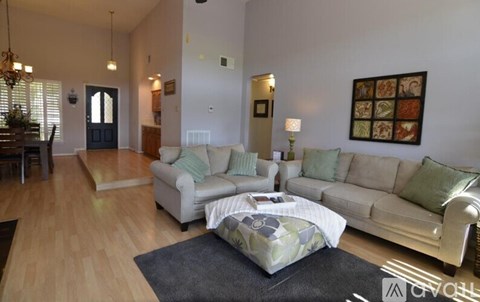 A living room with a white couch and a grey rug.