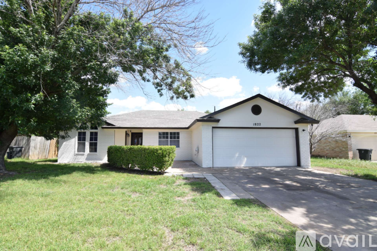 A two-story house with a garage is surrounded by a grassy yard.
