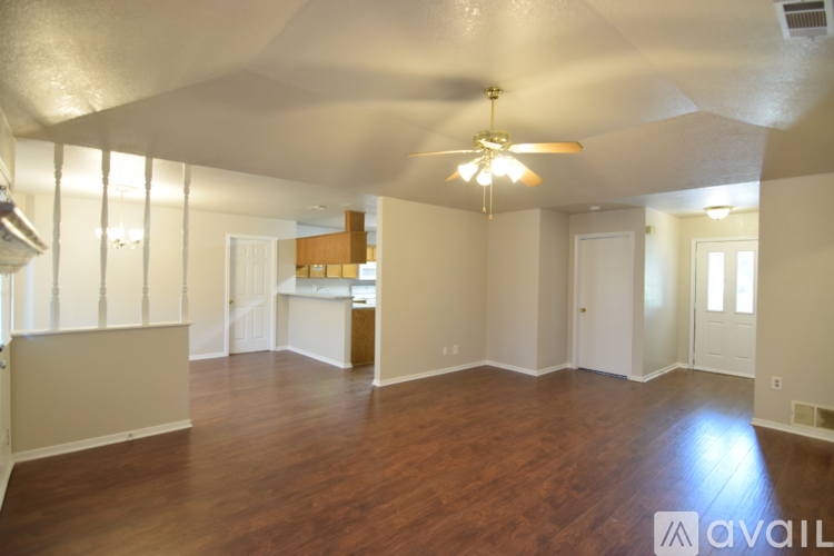 A spacious room with wooden floors and a ceiling fan.