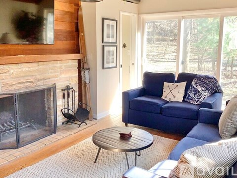 A blue couch with a pillow and a blanket on it sits in a living room.