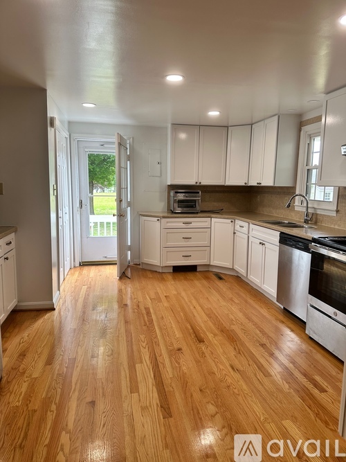 A kitchen with white cabinets and wooden floors.
