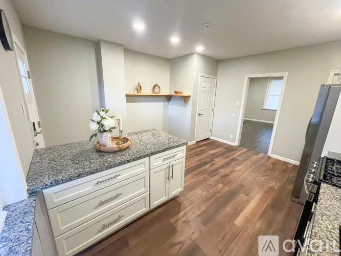 A kitchen with a granite countertop and wooden flooring.