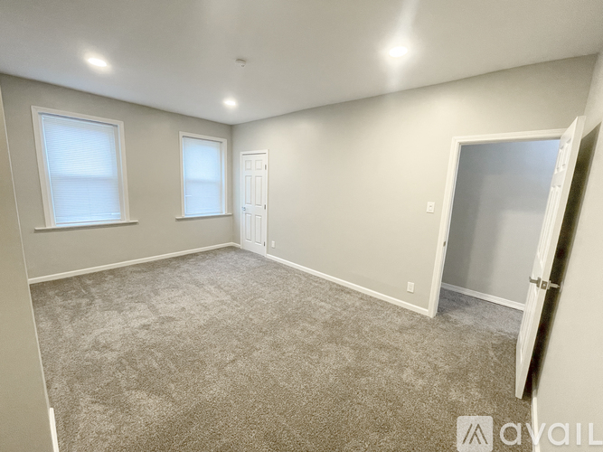 A spacious room with carpeted floor and white walls.