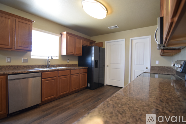 A kitchen with wooden cabinets and a black refrigerator.
