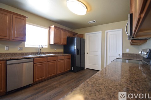 A kitchen with wooden cabinets and a black refrigerator.