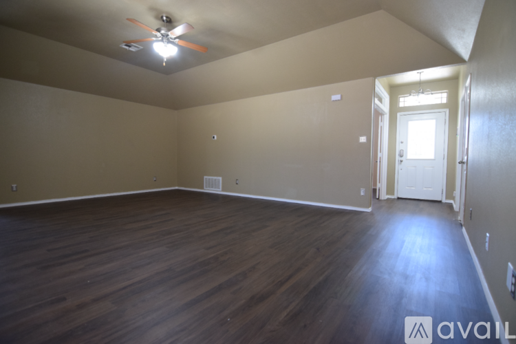 A spacious room with wooden flooring and a ceiling fan.