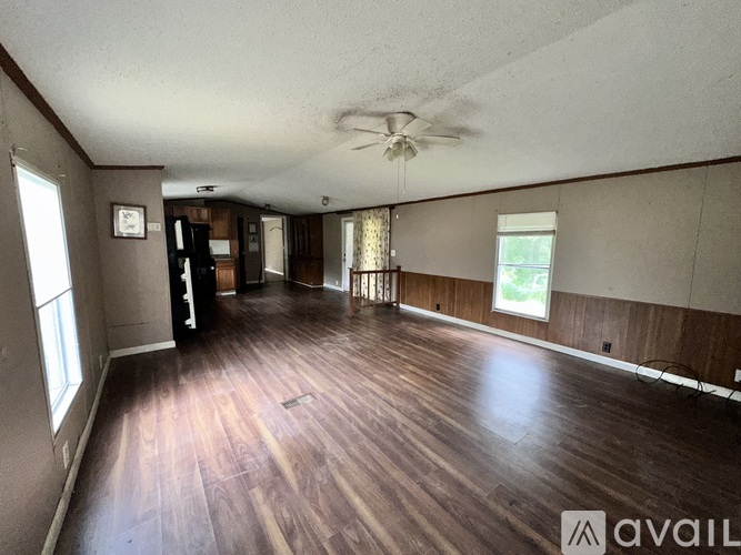 A spacious room with wooden floors and a ceiling fan.