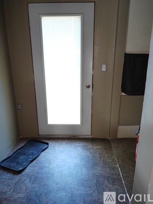 A room with a door and a mattress on the floor.