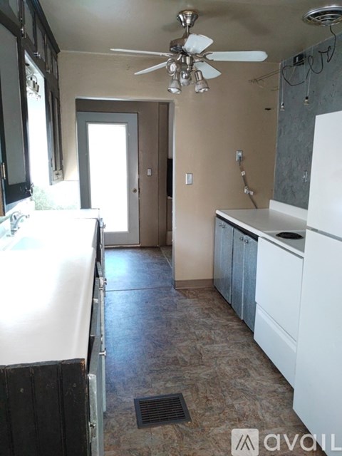 A kitchen with a white fridge and a fan on the ceiling.
