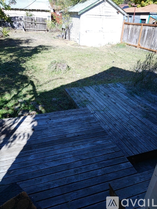 A wooden deck in a backyard with a white shed in the background.