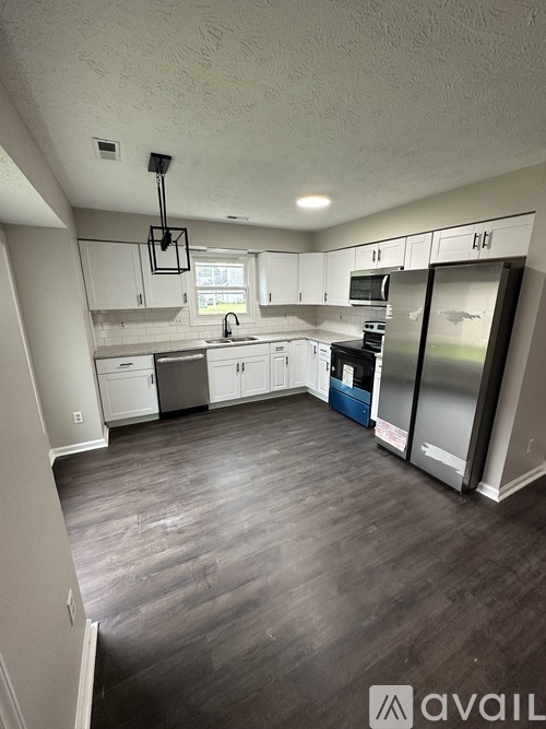 A kitchen with white cabinets and a wooden floor.