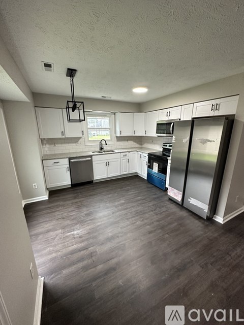 A kitchen with white cabinets and a wooden floor.