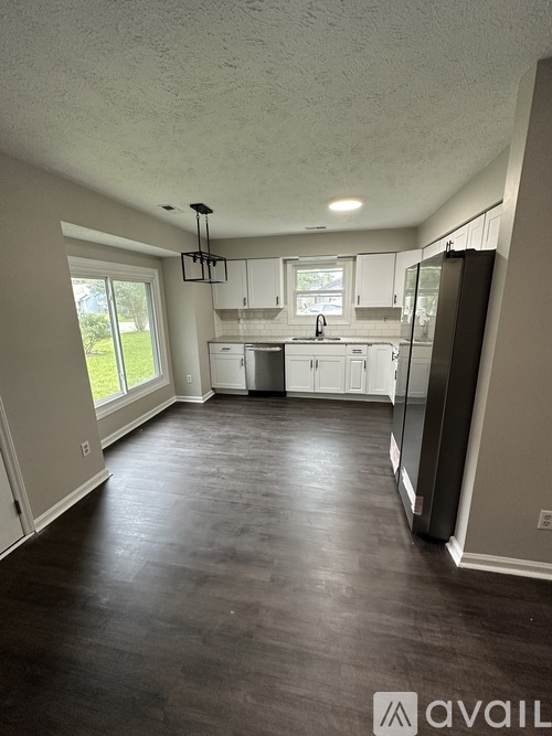 A kitchen with a refrigerator, sink, and cabinets.