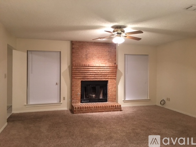 A living room with a fireplace and a ceiling fan.