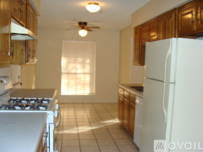A kitchen with a white refrigerator, stove, and wooden cabinets.