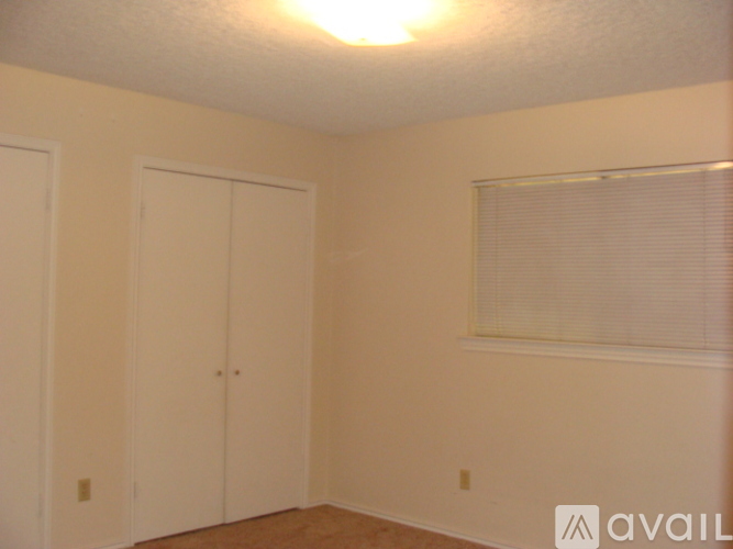 A room with two doors and a window with blinds.