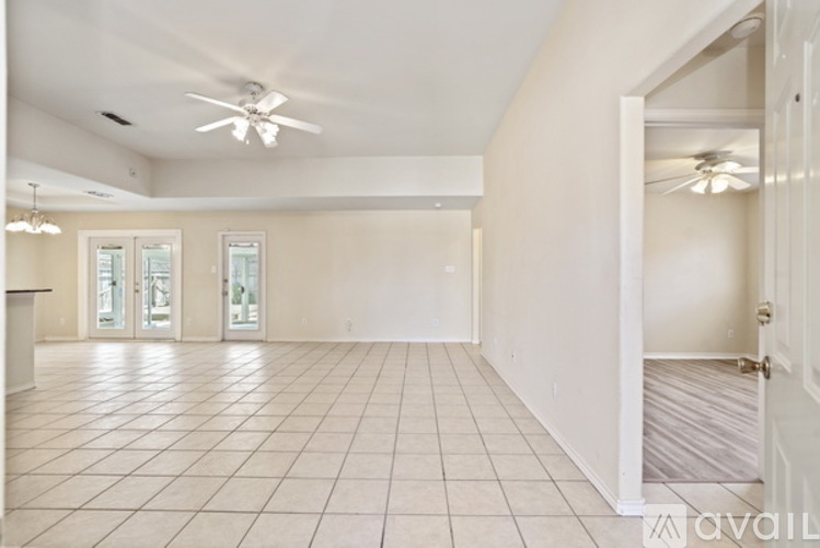 A spacious room with a ceiling fan and tiled flooring.