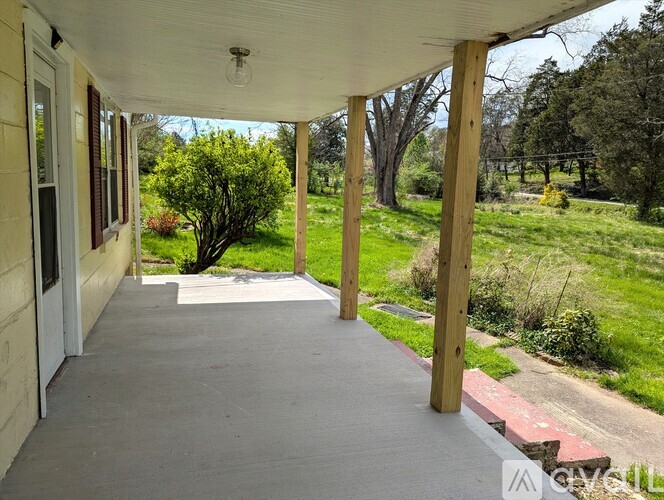A porch with a white ceiling and a concrete floor.
