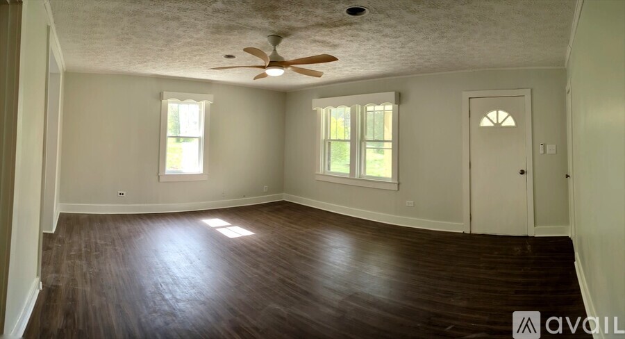 A room with a ceiling fan and wooden flooring.