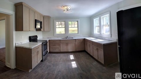 A kitchen with brown cabinets and a black refrigerator.