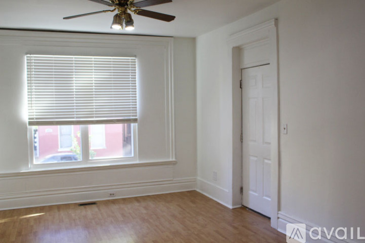 A room with a ceiling fan, a window with blinds, and a door.
