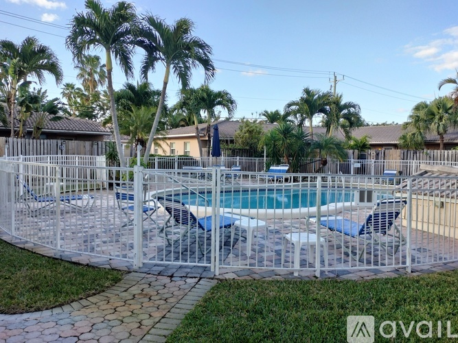 A pool surrounded by a white fence with palm trees in the background.