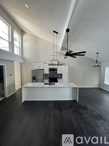 A modern kitchen with a marble island and pendant lights.