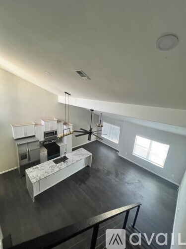 A modern kitchen with a marble island and a staircase leading to the upper floor.