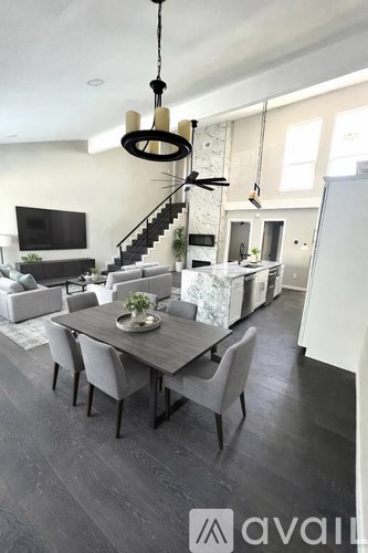 A modern kitchen with a marble island and a staircase leading to the upper floor.