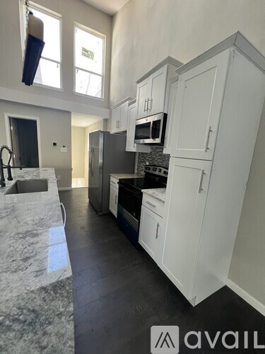 A kitchen with white cabinets and a marble countertop.