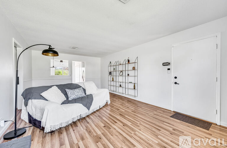 A bedroom with a bed, a lamp, and a wooden floor.
