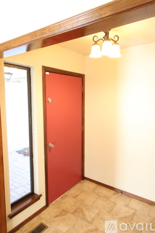 A red door is in a hallway with a tiled floor.